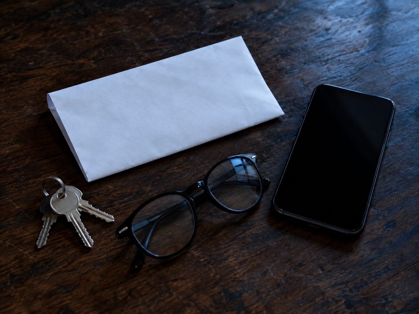Carta de intimação dobrada sobre a mesa, ao lado de um celular, chaves e óculos